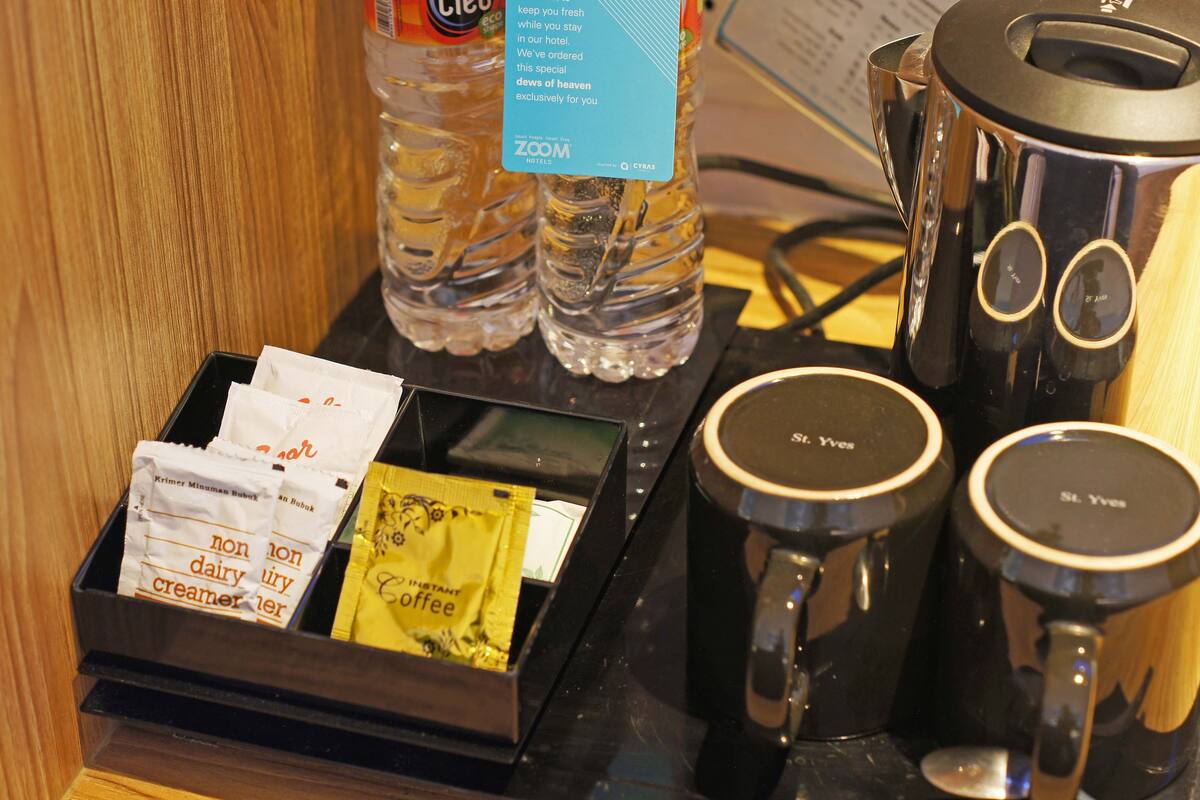 Una estación de café con sobres de café instantáneo, una botella de agua y una cafetera.