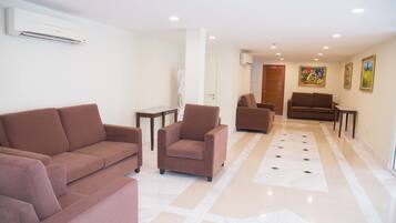 Un moderno vestíbulo de hotel con piso de baldosas color beige, sofás marrones y una puerta de madera.