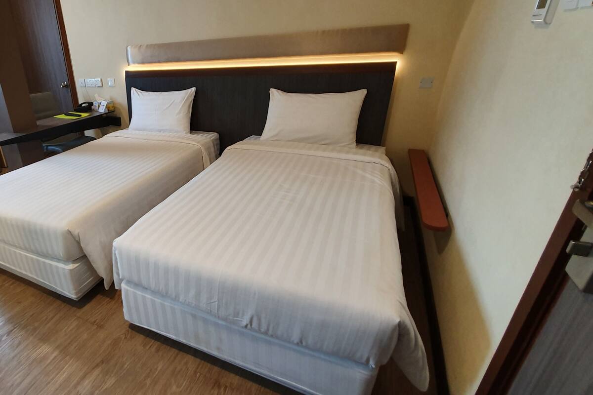 A hotel room with two beds, a desk, and a mirror.