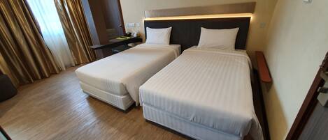 Habitación de hotel con dos camas, un escritorio y un espejo.