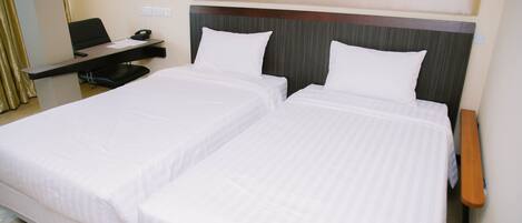 Una habitación de hotel con dos camas individuales, un escritorio con una silla y una mesita.