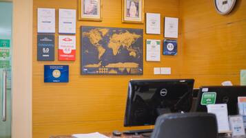 Un mostrador de recepción con una computadora, un mapa mundial y varios premios y certificados en la pared.