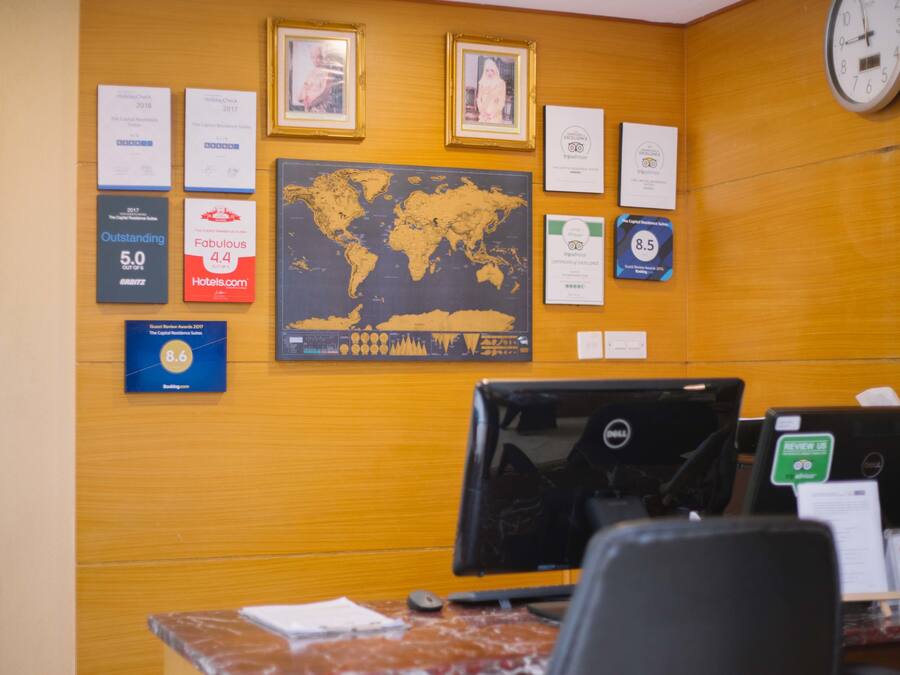 Un mostrador de recepción con una computadora, un mapa mundial y varios premios y certificados en la pared.