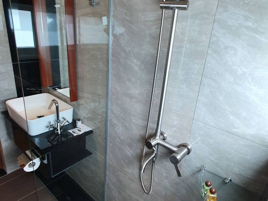 A modern bathroom with a glass-enclosed shower, a sink with a mirror, and a small shelf with toiletries.