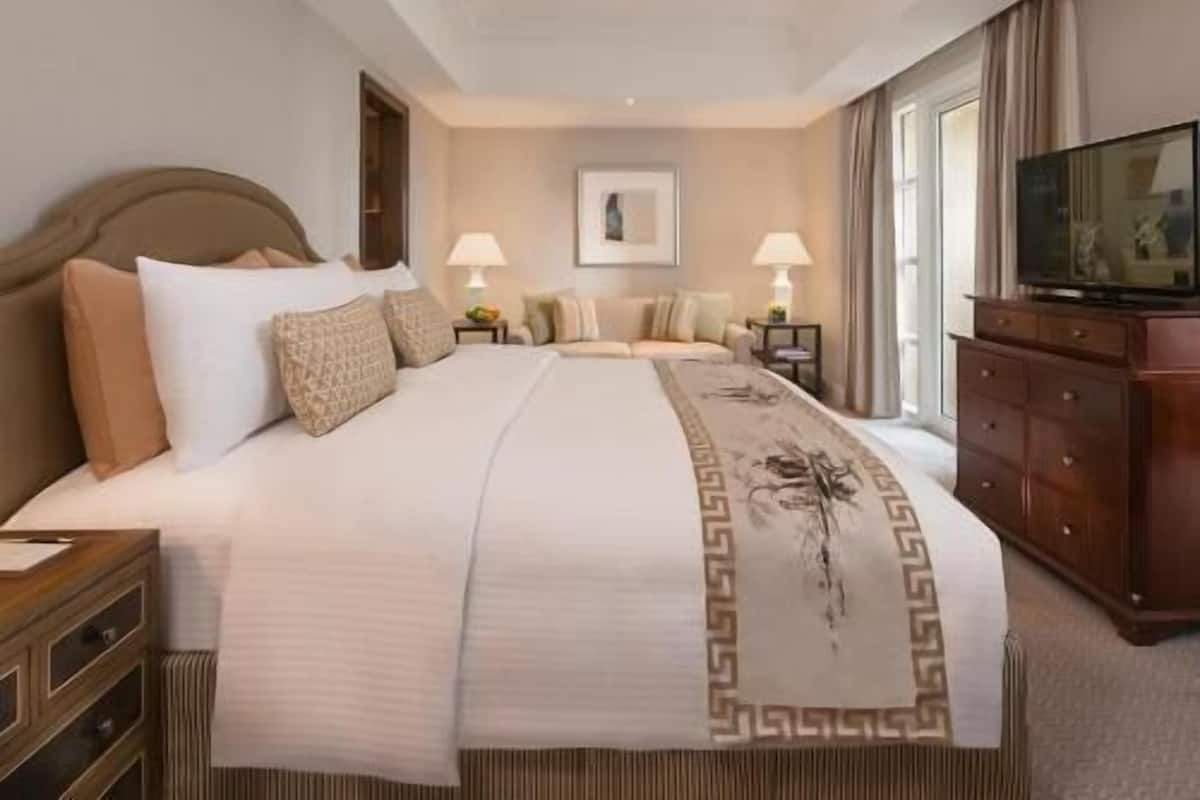 Una habitación de hotel con una cama grande, un televisor, un aparador y un escritorio.