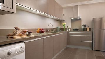 A modern kitchen with stainless steel appliances, a built-in oven, and a washing machine.