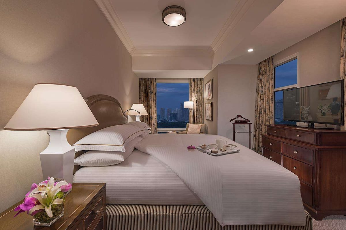 Habitación de hotel con una cama grande, televisor, cómoda y vista a la ciudad.