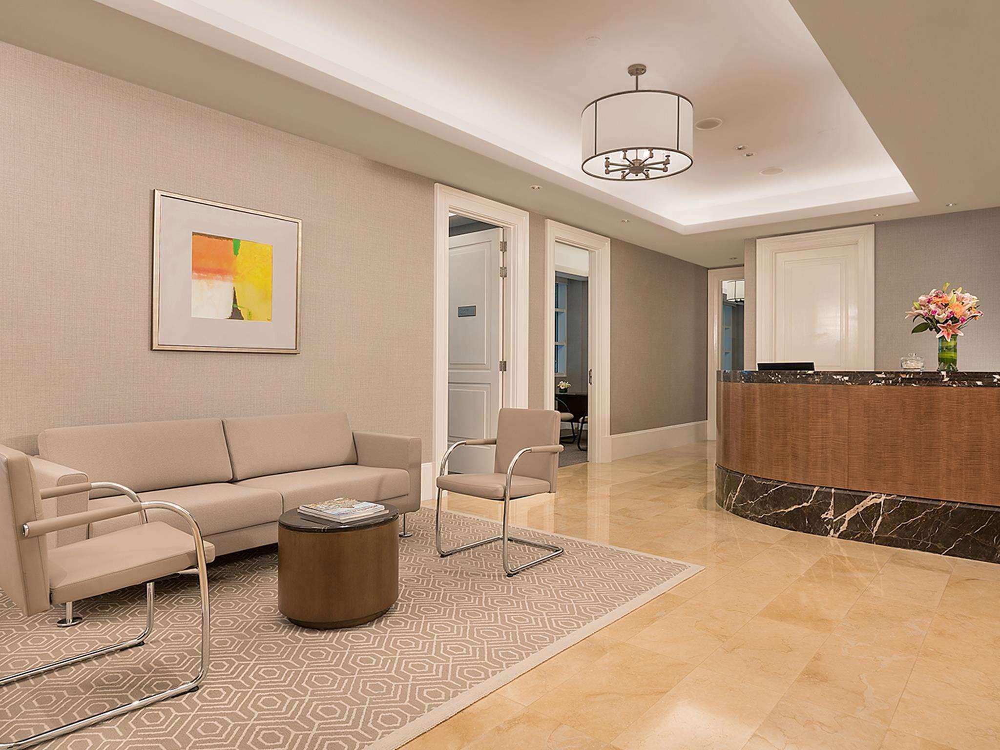 Un moderno vestíbulo de hotel con sofá, sillones, una mesa de centro, mostrador de recepción y una araña.