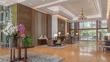 A spacious lobby with a reception desk, seating area, and large windows offering views of the outdoors.