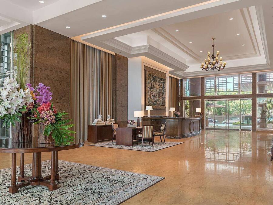 A spacious lobby with a reception desk, seating area, and large windows offering views of the outdoors.