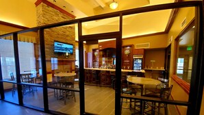 A restaurant with a bar area, dining tables, and chairs. - Clarion Hotel & Suites Williston (Williston)