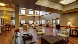 A spacious hotel lobby with leather sofas, armchairs, and a coffee table. - Clarion Hotel & Suites Williston (Williston)