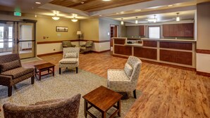 A lobby with a reception desk, seating area with patterned chairs, wooden flooring, and a ceiling with recessed lighting. - Clarion Hotel & Suites Williston (Williston)