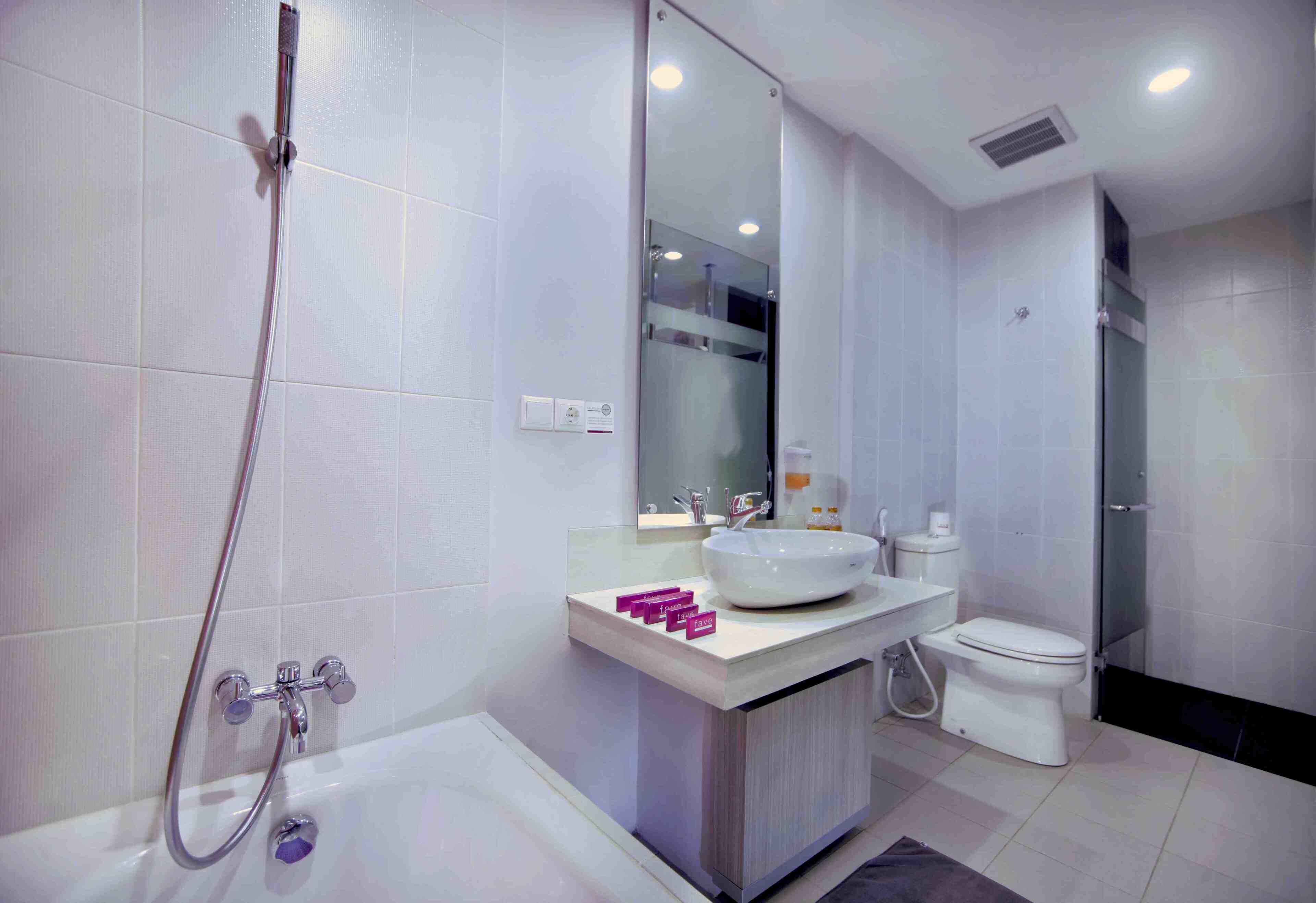Un baño moderno con bañera, lavamanos con espejo e inodoro.
