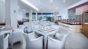 A modern cafe with white wicker furniture, a counter with various items, and a view of the outdoors.