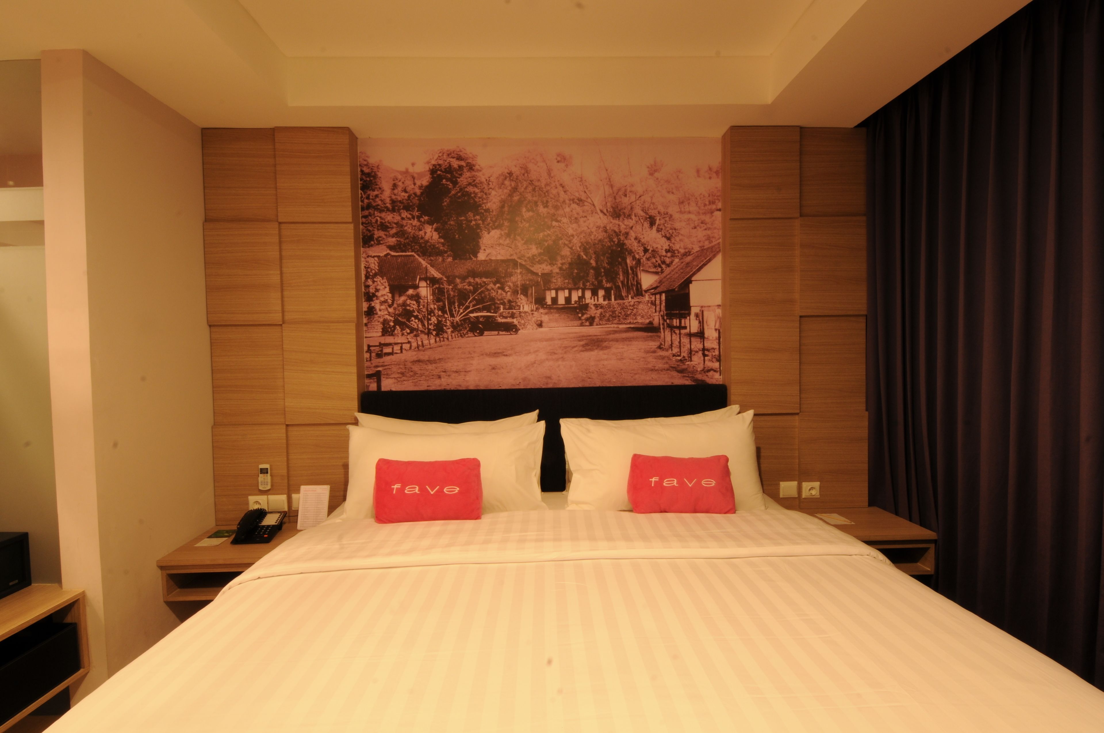 Una habitación de hotel con una cama, dos mesitas de noche, un teléfono y un tapiz grande en la pared.