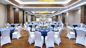 A large conference room with round tables, white chairs, and blue tablecloths.