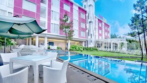 A hotel with a swimming pool, outdoor seating, and a garden area.