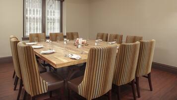 A conference room with a wooden table, striped chairs, and a cake centerpiece.