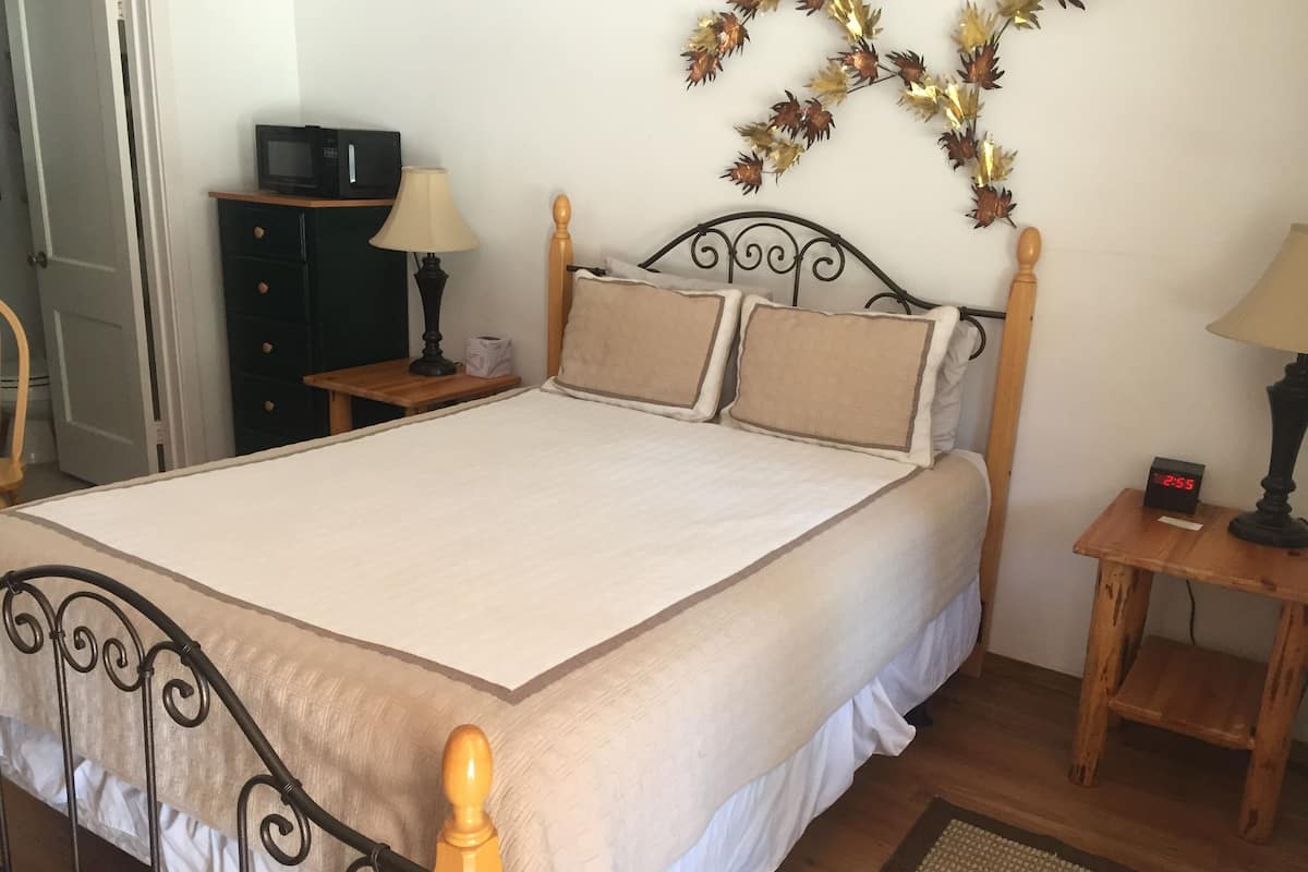 A neatly made bed with a wooden headboard, a bedside table with a lamp, and a decorative wall hanging.