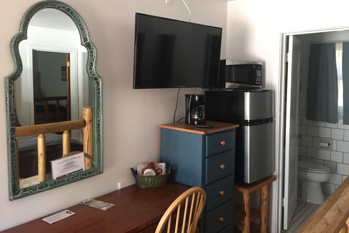 A compact kitchenette with a flat-screen TV, a coffee maker, and a microwave.