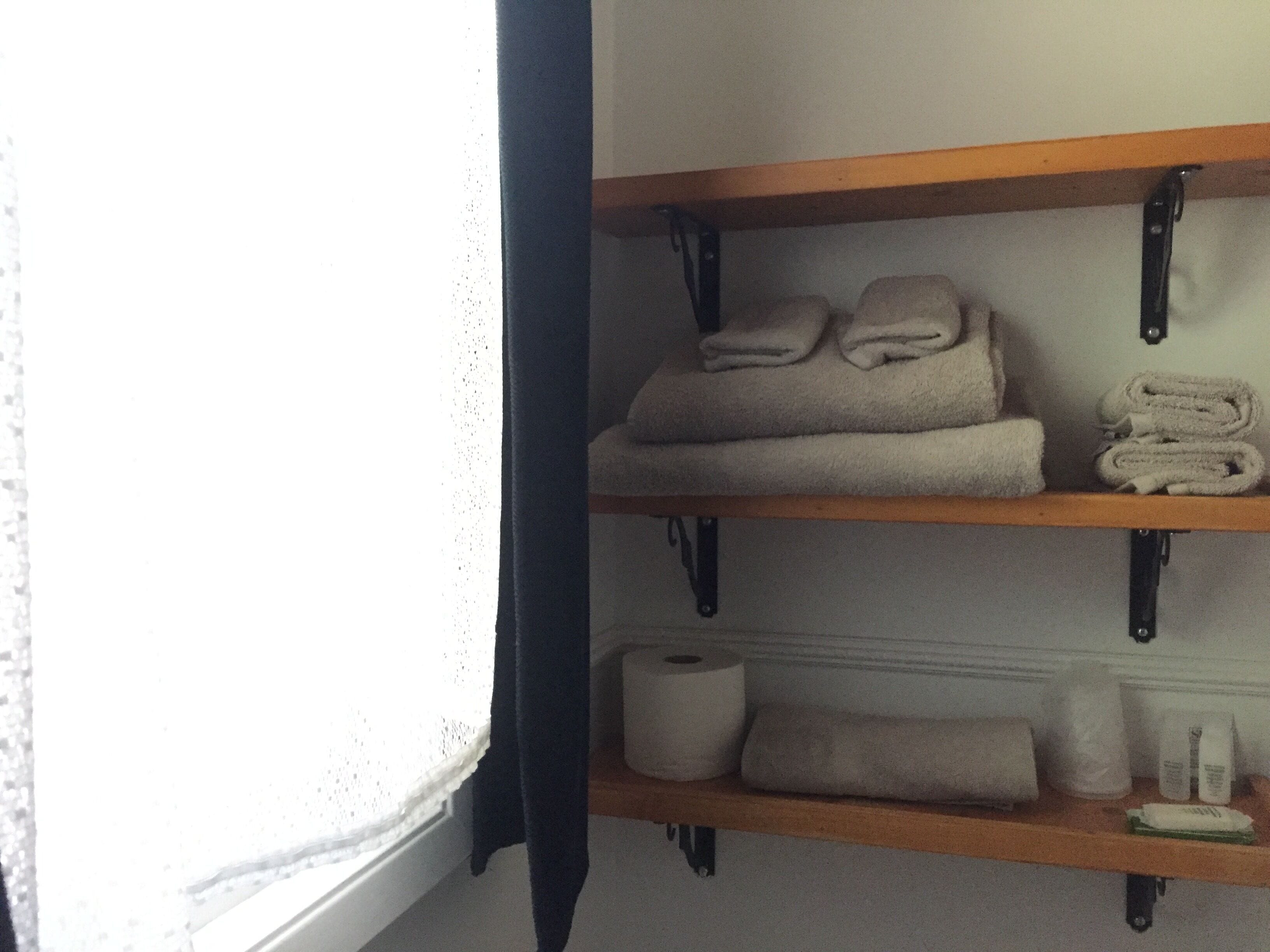 A shelf with folded towels and a roll of toilet paper.