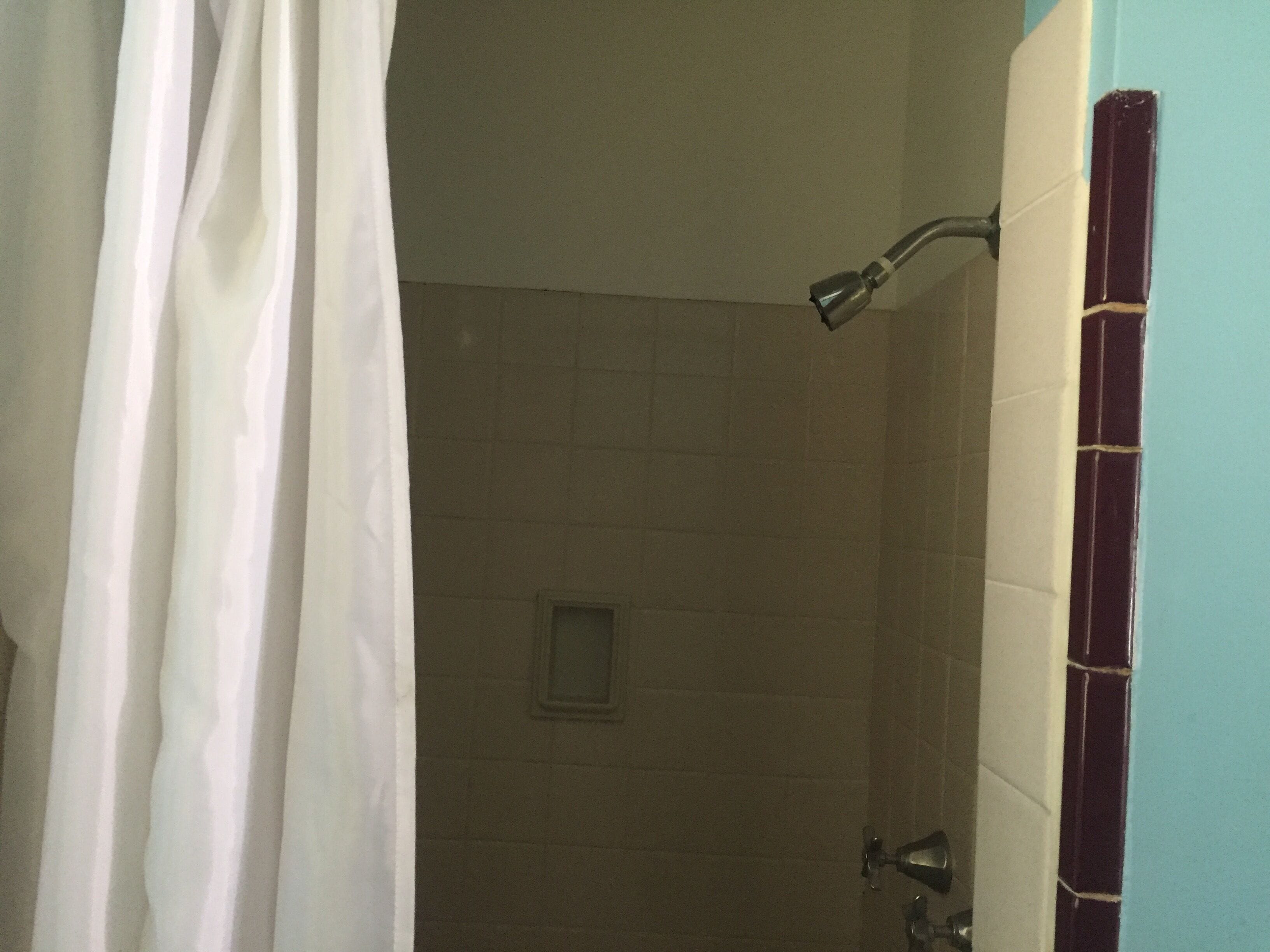 A bathroom with a shower, tiled walls, and a curtain.