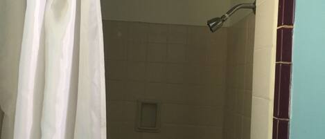 Une salle de bain avec une douche, des murs carrelés et un rideau.