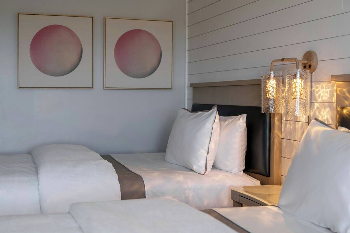 Une chambre d’hôtel avec un lit, une table de chevet et une lampe fixée au mur.