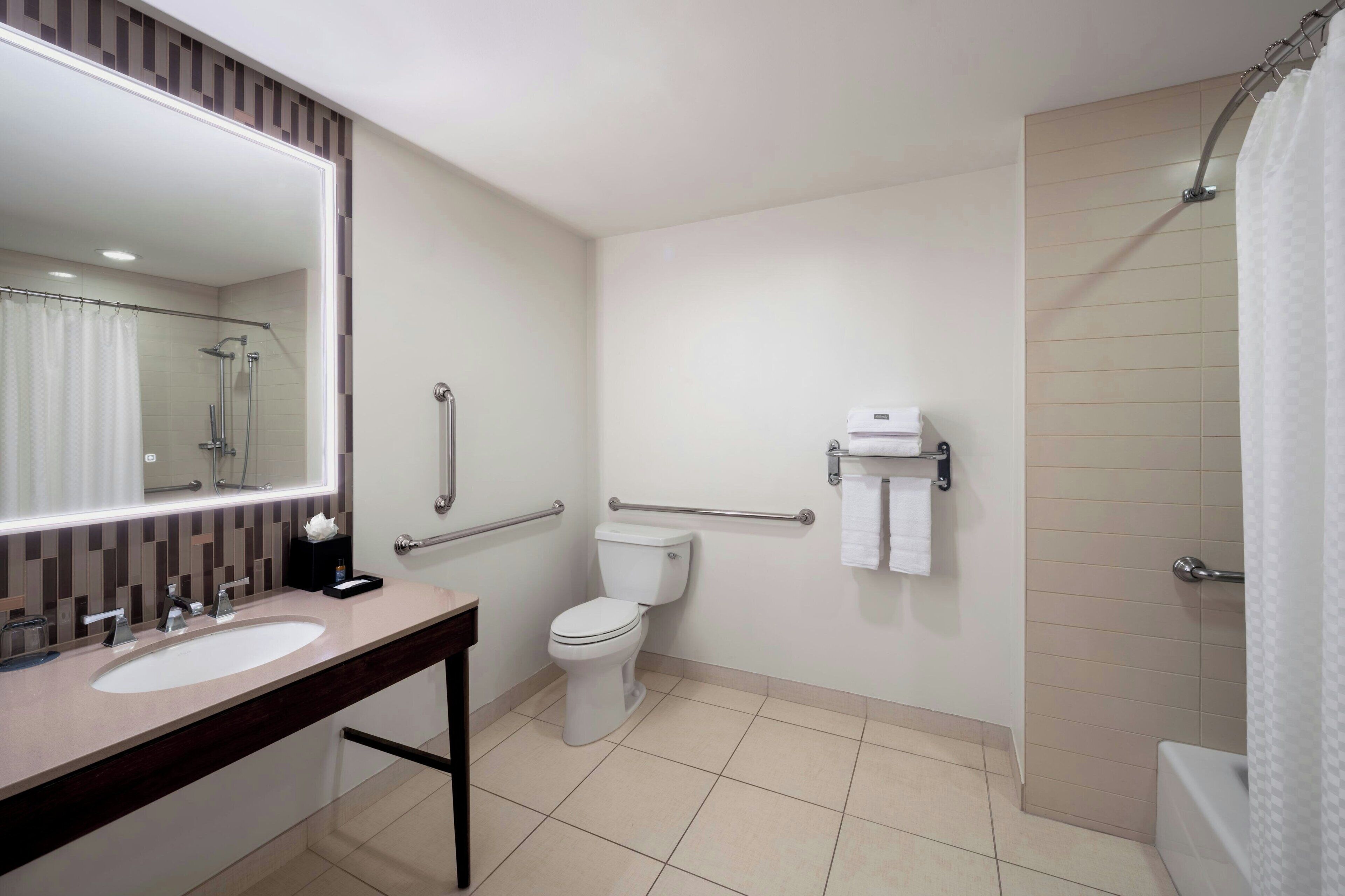 Un baño moderno con lavamanos, inodoro y ducha.