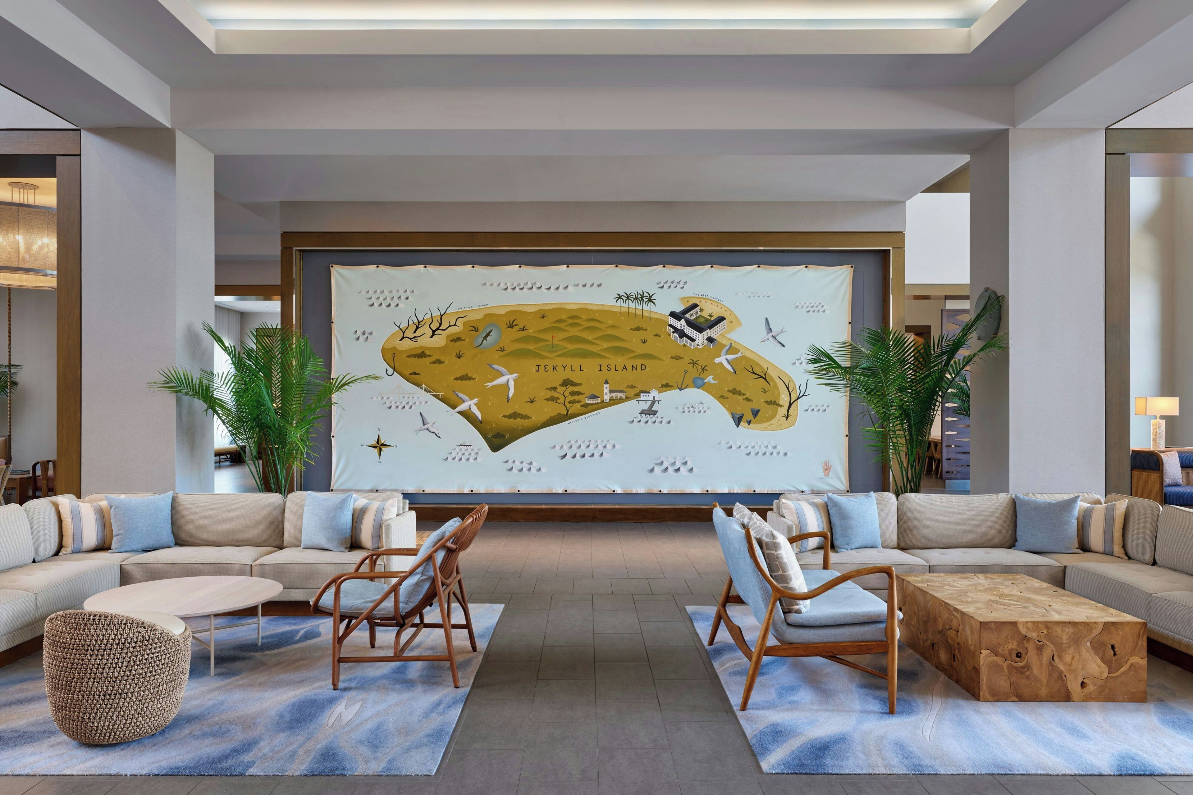 A modern lobby with a large wall mural, seating area, and a wooden coffee table.