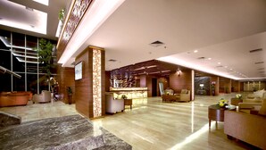 A spacious lobby with a reception desk, seating area, and a staircase leading to an upper level. - Aston Madiun Hotel & Conference Center (Madiun)