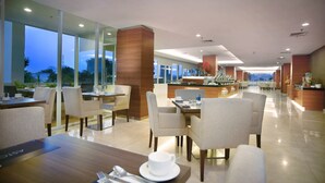 A modern hotel lobby with a dining area, large windows, and a reception desk. - Aston Madiun Hotel & Conference Center (Madiun)