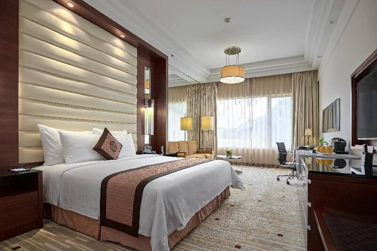 A hotel room with a large bed, a desk, a chair, and a television.