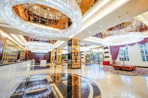 A spacious lobby with a central circular reflective floor, multiple chandeliers, and a seating area with a red upholstered sofa. - Royal Halong Hotel (Bai Chay)