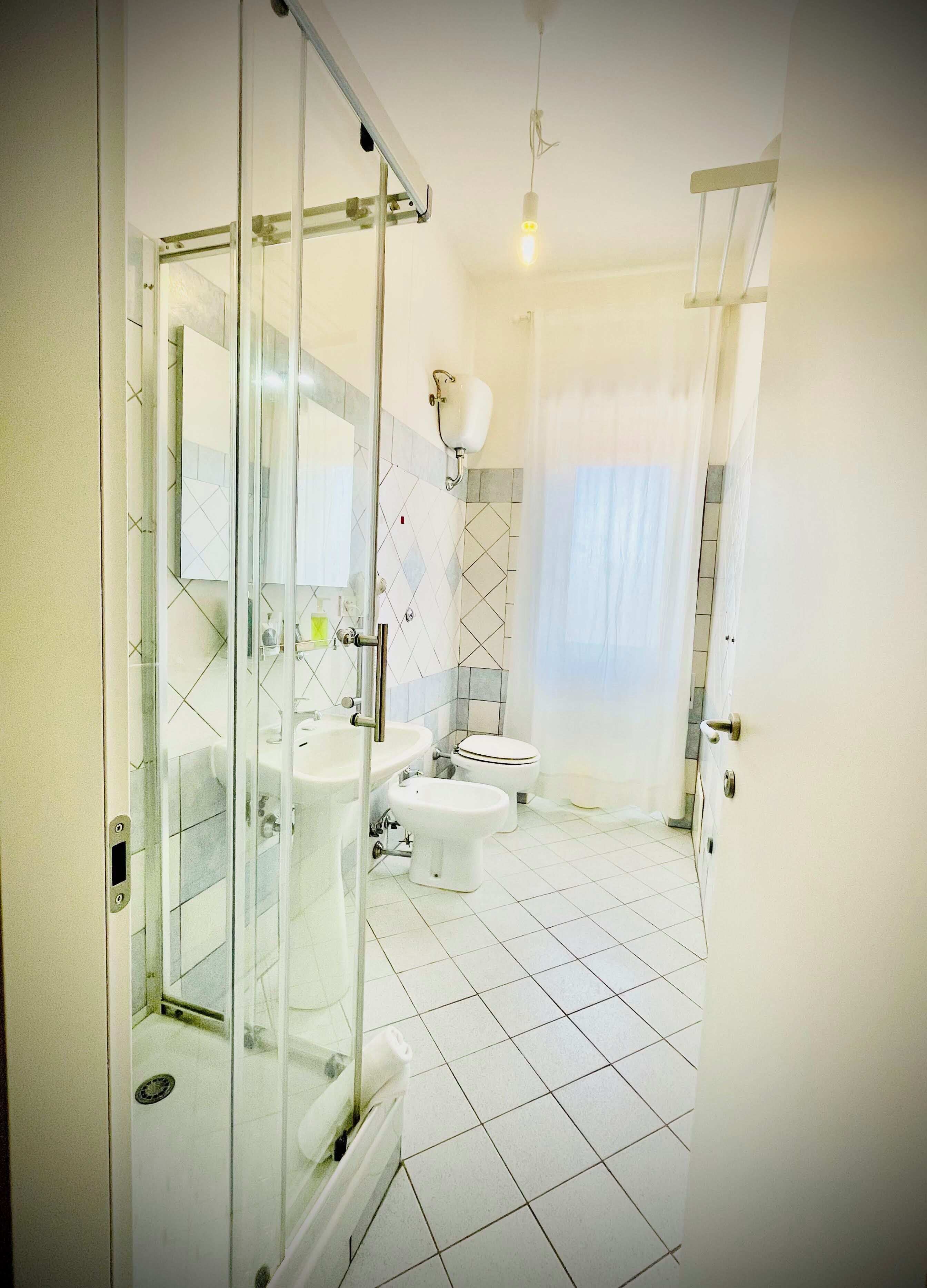 Une salle de bain avec une douche à parois de verre, des toilettes, un lavabo et un miroir.
