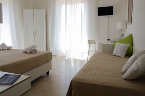 A hotel room with two beds, a desk, a chair, a TV, and a wardrobe. - Minturnae Hotel (Minturno)