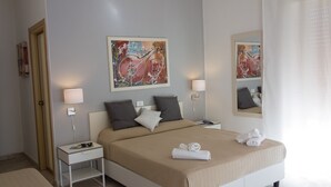 A modern hotel room with a large bed, two bedside tables with lamps, a mirror, and abstract artwork on the walls. - Minturnae Hotel (Minturno)