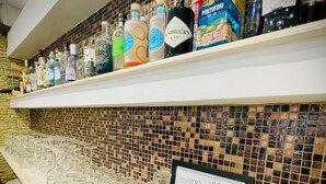 A bar area with shelves stocked with various liquor bottles and a tray with glasses and shot glasses. - Minturnae Hotel (Minturno)