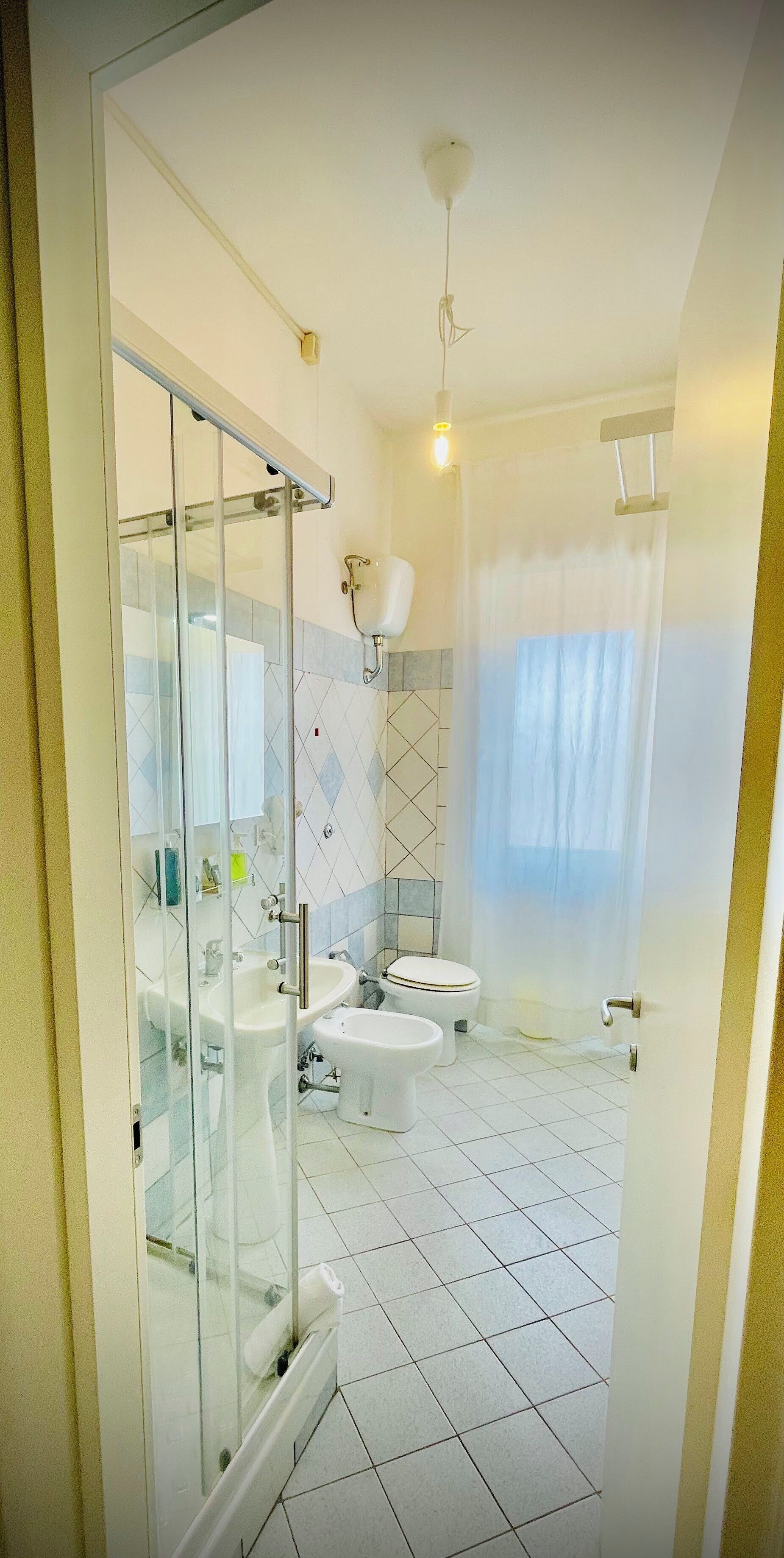 Un bagno moderno con box doccia in vetro, un water, un bidet e un lavandino.