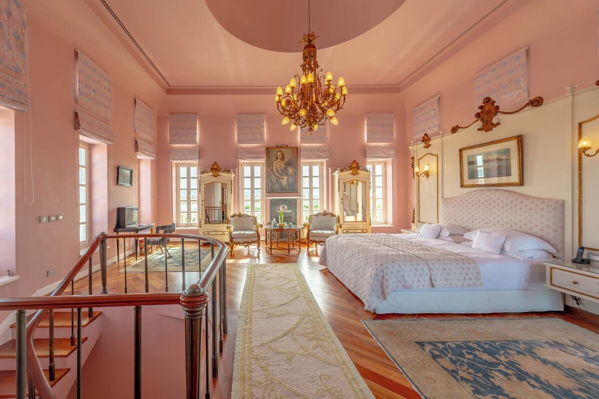 Un dormitorio amplio con una cama grande, un candelabro y vistas a la ciudad.