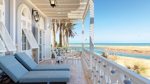 A beachside lounge with a view of the sea, featuring a white railing, lounge chairs, and a pergola with a lantern. - La Maison Bleue (El Gouna)