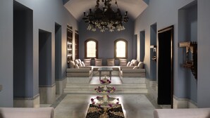 A spacious hallway with a seating area, a chandelier, and a fountain. - La Maison Bleue (El Gouna)