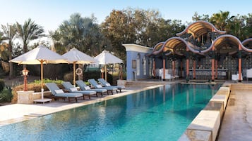 Alberca al aire libre, alberca con cascada y sombrillas en la alberca