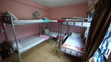 A bunk room with three bunk beds, a fan, and a window with curtains.