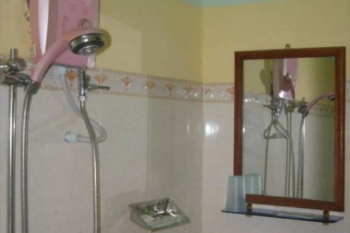 Un baño con ducha, espejo y jabonera.