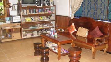 A living room with a wooden sofa, a coffee table, and a bookshelf filled with books.