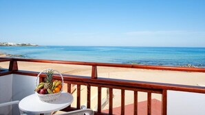 A balcony with a wicker basket of fruit, a white chair, and a view of the beach and ocean. - Vlachakis Hotel (Hersonissos)