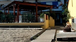 A beachside building with a wooden deck leading to a covered seating area. - Vlachakis Hotel (Hersonissos)