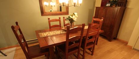 A dining room with a wooden table and chairs, a chandelier, and a mirror on the wall.